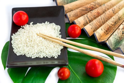 Oriental composition of rice, tomatoes, chopsticks, green leaf and transp isolated on white background