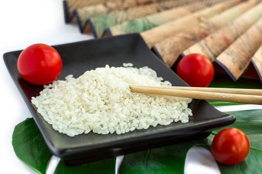 Oriental composition of rice, tomatoes, chopsticks, green leaf and transp isolated on white background