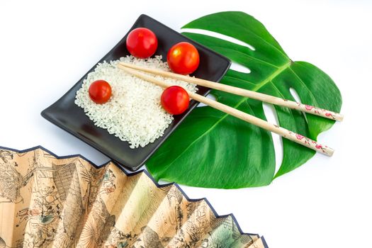 Oriental composition of rice, tomatoes, chopsticks, green leaf and transp isolated on white background