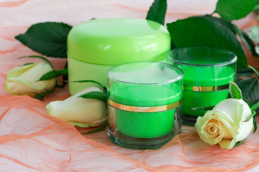 Set of three green cosmetic cream bottles with white roses