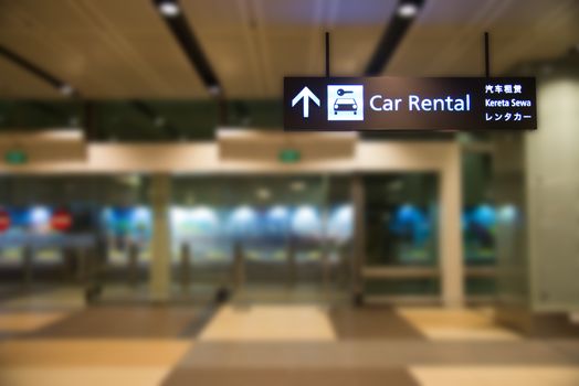 blue illuminated rental car sign with blur background