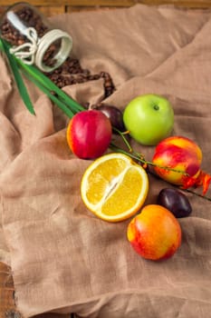 Still life on sacking background: apple, peaches, orance, plums