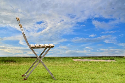 Old chair on green grass in blue sky background
