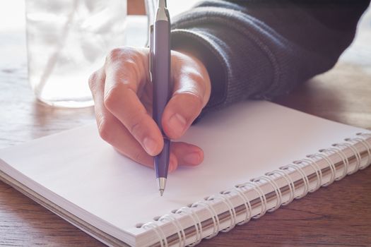 Woman hand with pen writing on notebook with vintage style