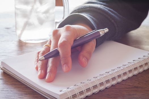 Woman hand with pen writing on notebook with vintage style