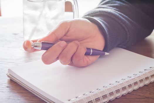 Woman hand with pen writing on notebook with vintage style