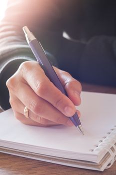 Woman hand with pen writing on notebook with vintage style