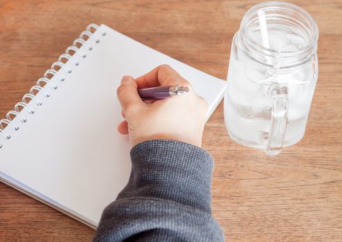 Woman hand with pen writing on notebook, stock photo