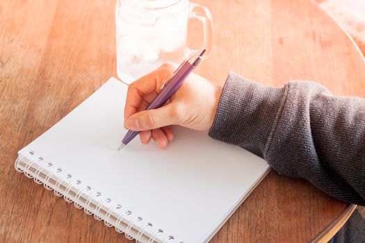 Woman hand with pen writing on notebook, stock photo