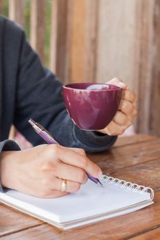 Woman hand with pen writing on notebook, stock photo