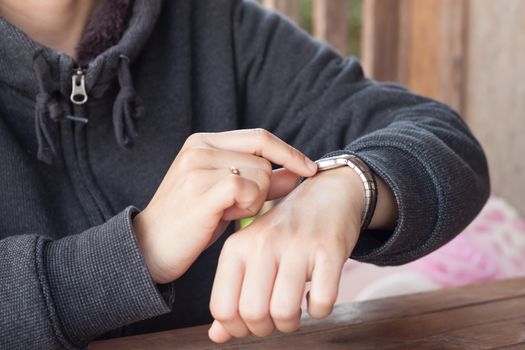 Woman checks the time on a wrist watch, stock photo