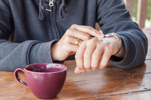 Woman checks the time on a wrist watch, stock photo