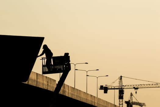Silhouette of construction worker on scaffolding in the construction site before to night time.
