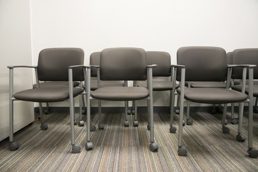 Closeup on row of empty chairs at the reception waiting area of an interior office building.