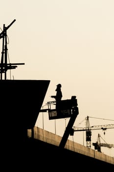 Silhouette of construction worker on scaffolding in the construction site before to night time.