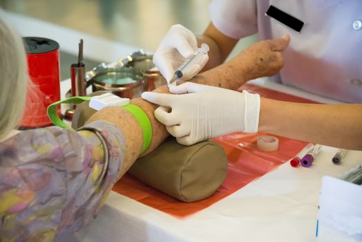 Nurse taking blood sample from patient at the doctors office.