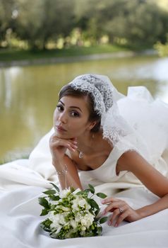 The beautiful bride with bouquet in park