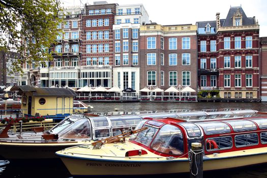 AMSTERDAM, THE NETHERLANDS - AUGUST 19, 2015: View on Hotel de l'Europe and Amstel street from Halvemaansbrug. Street life, Canal, bicycle and boat in Amsterdam. Amsterdam is capital of the Netherlands on August 19, 2015.