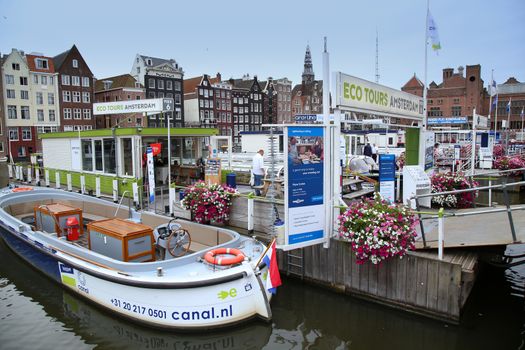 AMSTERDAM; THE NETHERLANDS - AUGUST 16; 2015: Beautiful views of the ancient buildings at the waterside, canal and boats, Damrak canal in Amsterdam, The Netherlands on August 16; 2015.