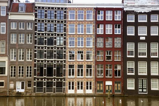 AMSTERDAM; THE NETHERLANDS - AUGUST 16; 2015: Beautiful views of the ancient buildings at the waterside, Damrak canal in Amsterdam. Amsterdam is capital of the Netherlands on August 16; 2015.