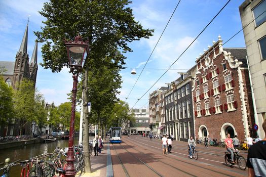 AMSTERDAM; THE NETHERLANDS - AUGUST 19; 2015: View of Singel street and De Krijtberg church from Koningsplein. Street life, canal, pedestrians, tram and bicycle, Amsterdam is capital of the Netherlands on August 19; 2015.