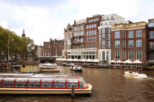 AMSTERDAM, THE NETHERLANDS - AUGUST 19, 2015: View on Hotel de l'Europe and Amstel street from Halvemaansbrug. Street life, Canal, bicycle and boat in Amsterdam. Amsterdam is capital of the Netherlands on August 19, 2015.