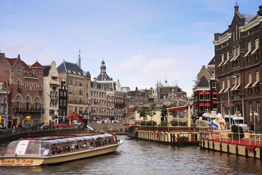 AMSTERDAM, THE NETHERLANDS - AUGUST 19, 2015: View on Rokin from bridge Doelensluis. Street life, Canal, tourists, bicycle and boat in Amsterdam. Amsterdam is capital of the Netherlands on August 19, 2015.