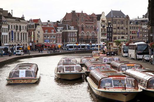 AMSTERDAM, THE NETHERLANDS - AUGUST 18, 2015: View on Rokin from bridge Doelensluis. Street life, Canal, tourists, bicycle and boat in Amsterdam. Amsterdam is capital of the Netherlands on August 18, 2015.