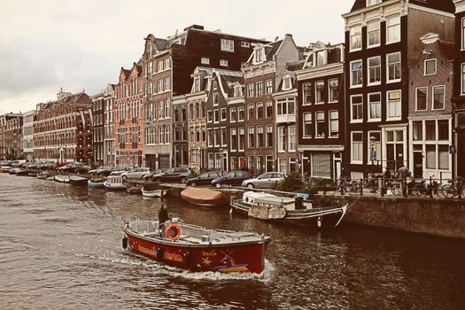 AMSTERDAM, THE NETHERLANDS - AUGUST 18, 2015: Street life and typical picture of canals in Amsterdam. Canal, bicycle and boat in Amsterdam. Amsterdam is capital of the Netherlands on August 18, 2015.