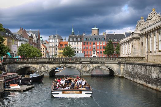 COPENHAGEN, DENMARK - AUGUST 14, 2016: View of canal, boat with tourist and old bridge from bridge Prinsens Bro in Copenhagen, Denmark on August 14, 2016.