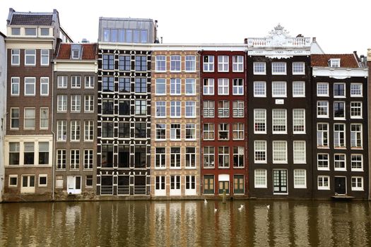 AMSTERDAM; THE NETHERLANDS - AUGUST 16; 2015: Beautiful views of the ancient buildings at the waterside, Damrak canal in Amsterdam. Amsterdam is capital of the Netherlands on August 16; 2015.

