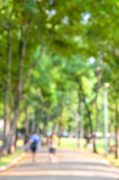 Blurred background of park with running people