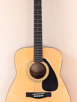 Acoustic guitar on orange wall background, stock photo