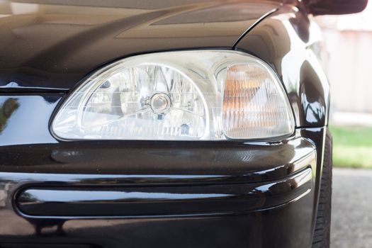 Closeup headlight of black coupe, stock photo