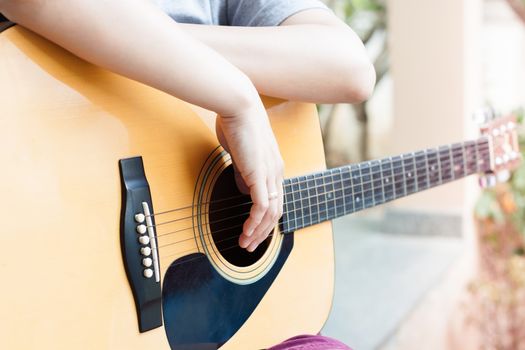 Woman's hands with acoustic guitar in relax post, stock photo