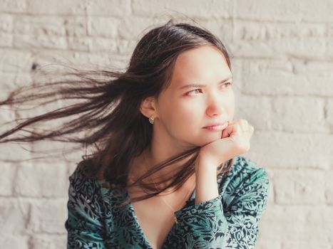 Stern and serious looking away young brunette beauty. Closeup portrait of serious young woman with sensual look away. Girl rests her chin on hand and serious looking away