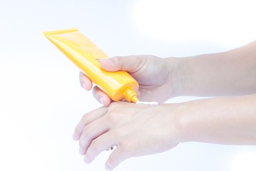 Woman pouring body lotion on hand on white background