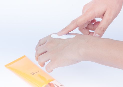 Woman pouring body lotion on hand on white background