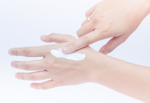 Woman pouring body lotion on hand on white background