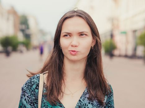 displeased handsome young woman with grimace looking away outdoors