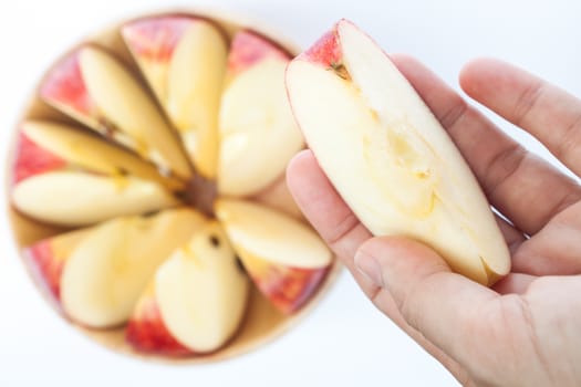 Woman hand holding piece of apple on white background