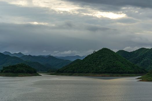 landscape with mountains trees and a river in front.