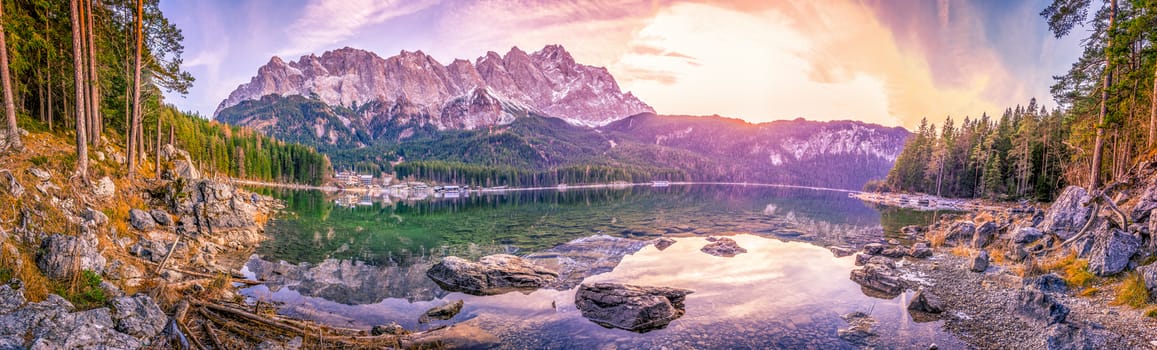 Panoramic view with the bavarian Alps mountains mirrored in the water of the Eibsee lake, located in Grainau, Germany, at dusk.