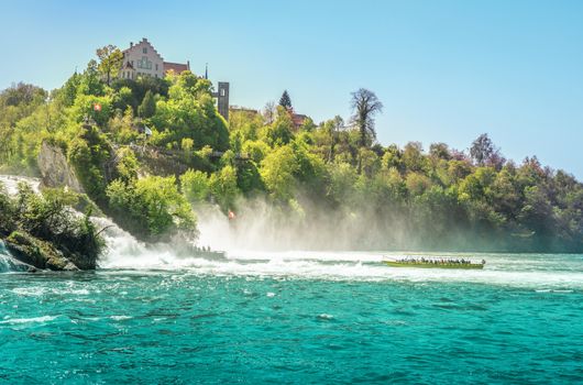 Boat enters the cloud of vapors made by the falling of the Rhine river, at the foot of the Laufen castle, Switzerland.