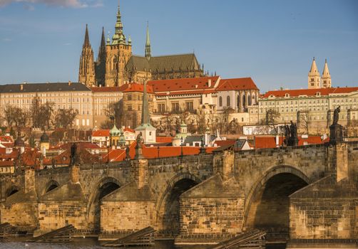 Close up with the stone built Charles Bridge and the St. Vilus Cathedral, surrounded by other historical buildings, in the background.