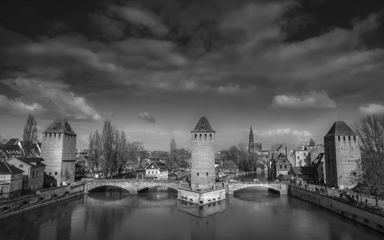 Black and white image of "Les ponts couverts" (the covered bridges), Strasbourg, Alsace, France, with a dramatic cloudscape.