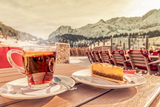 Picture of a hot cup of tea, with a slice of orange and a delicious cake served at a mountain restaurant, in Ehrwald, Austria.