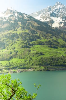 Landscape with the morning sun illuminating softly the lake Walensee and the snowy Swiss mountain peaks. Image taken from the village Quentin, Switzerland.