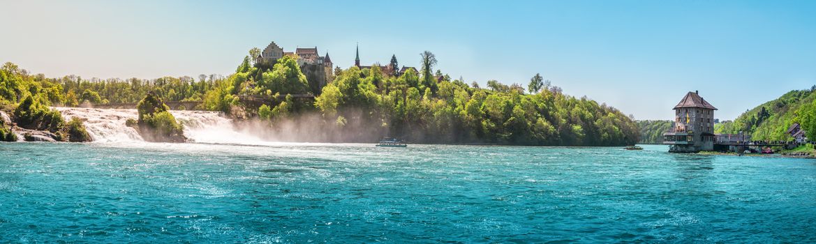 Panorama with the Rhienfall, the Laufen castle and Worth Castle, while boats navigate the blue waters of the river, in Switzerland.