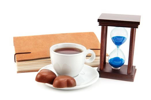 hourglass tea cup and a book on a white background